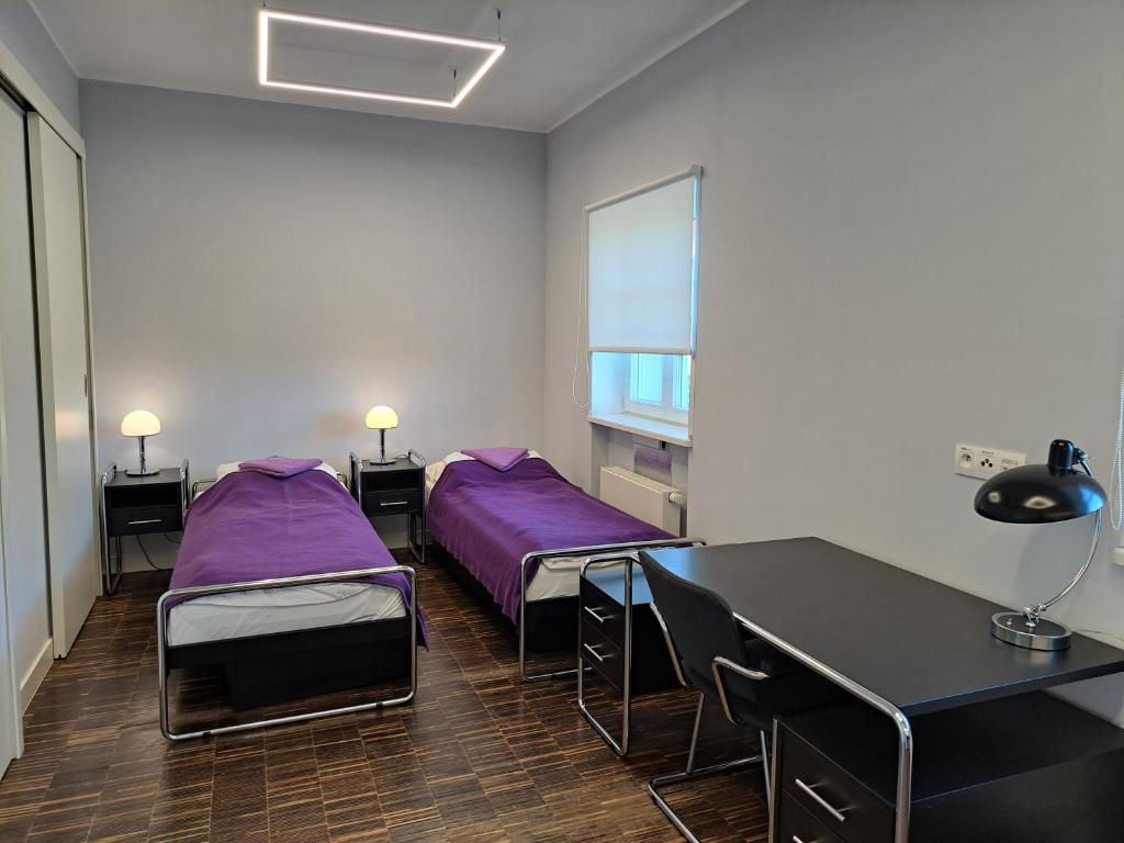 a room with two beds and a table with purple sheets at Dom Studencki Hanka in Poznań