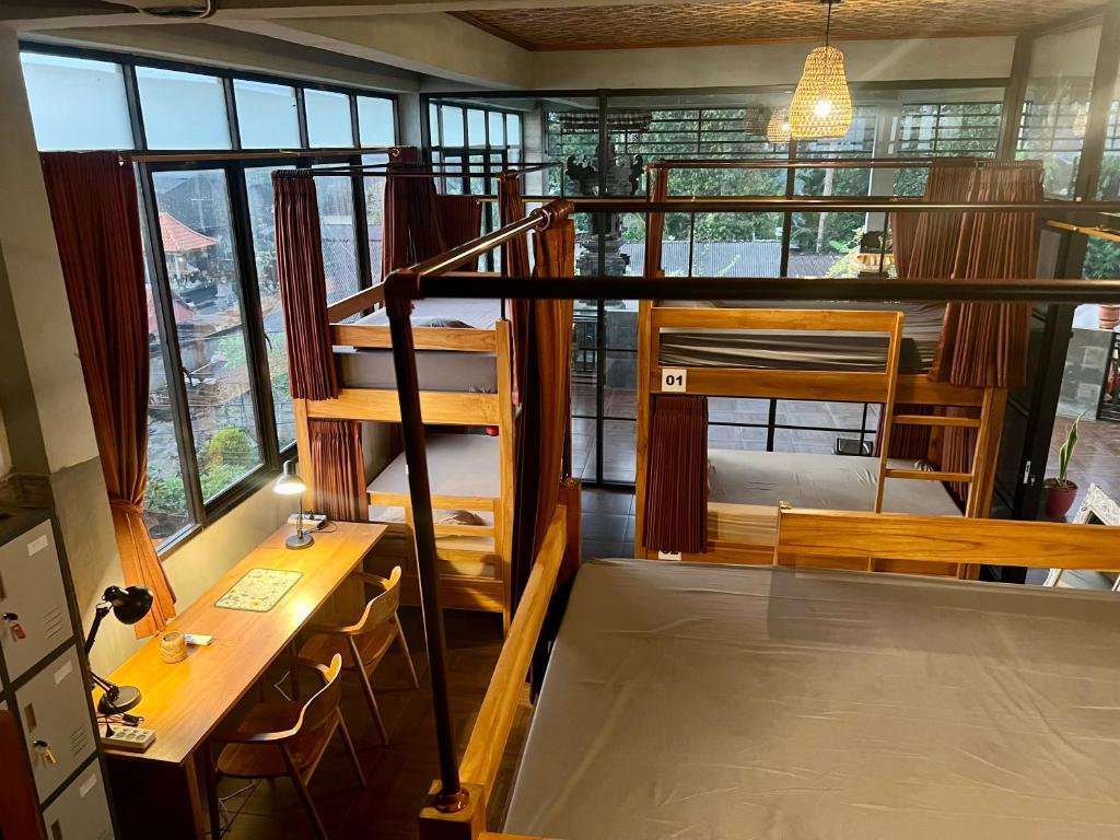 a room with bunk beds in a room with windows at Hostel KARMA by SEAOM Villas in Ubud