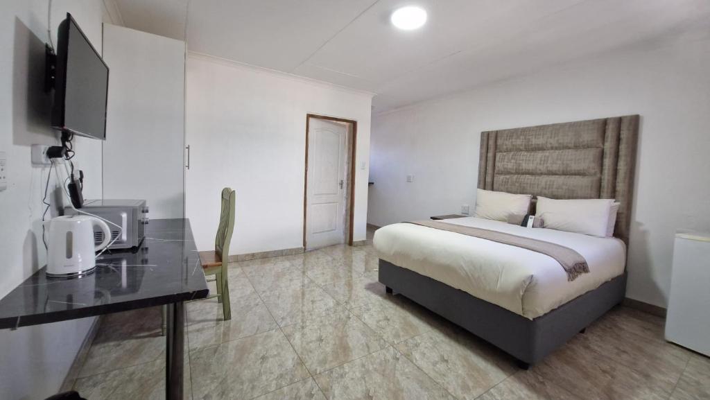 a bedroom with a bed and a desk with a television at 7th Heaven Boutique Hotels in Burgersfort
