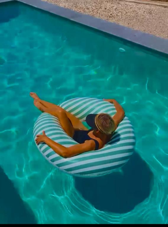 a woman laying on a raft in a swimming pool at Sea You Soon & Spa 1 in Methana