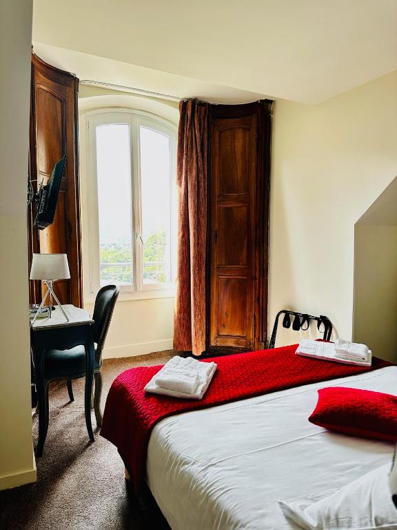a bedroom with a bed and a desk and a window at Hôtel Restaurant Le Repère in Vizille