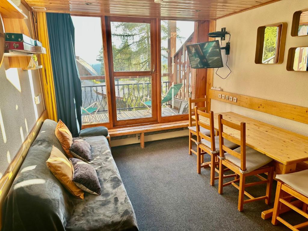 a living room with a couch and a table and a window at Duplex arcs 1800 aux pieds des pistes in Arc 1800