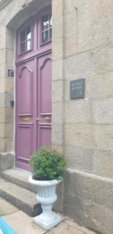 a purple door and a vase in front of a building at Des fleurs au balcon in Quintin