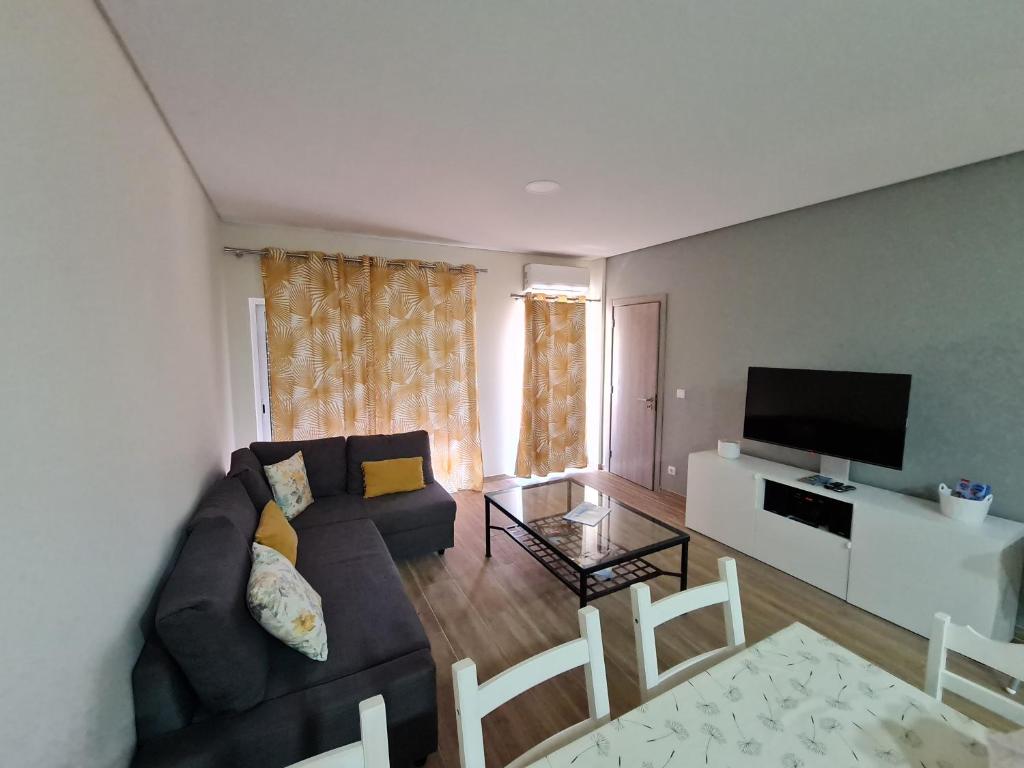 een woonkamer met een bank en een flatscreen-tv bij Casa Amarela - Albufeira in Albufeira
