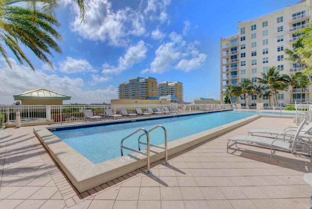 a swimming pool with chairs and a building at One Bedroom In Lux Condo,casa Costa! Wbeachpass! in Boynton Beach