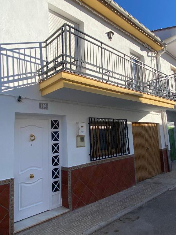 a white building with a balcony and a door at La Torre in Tózar