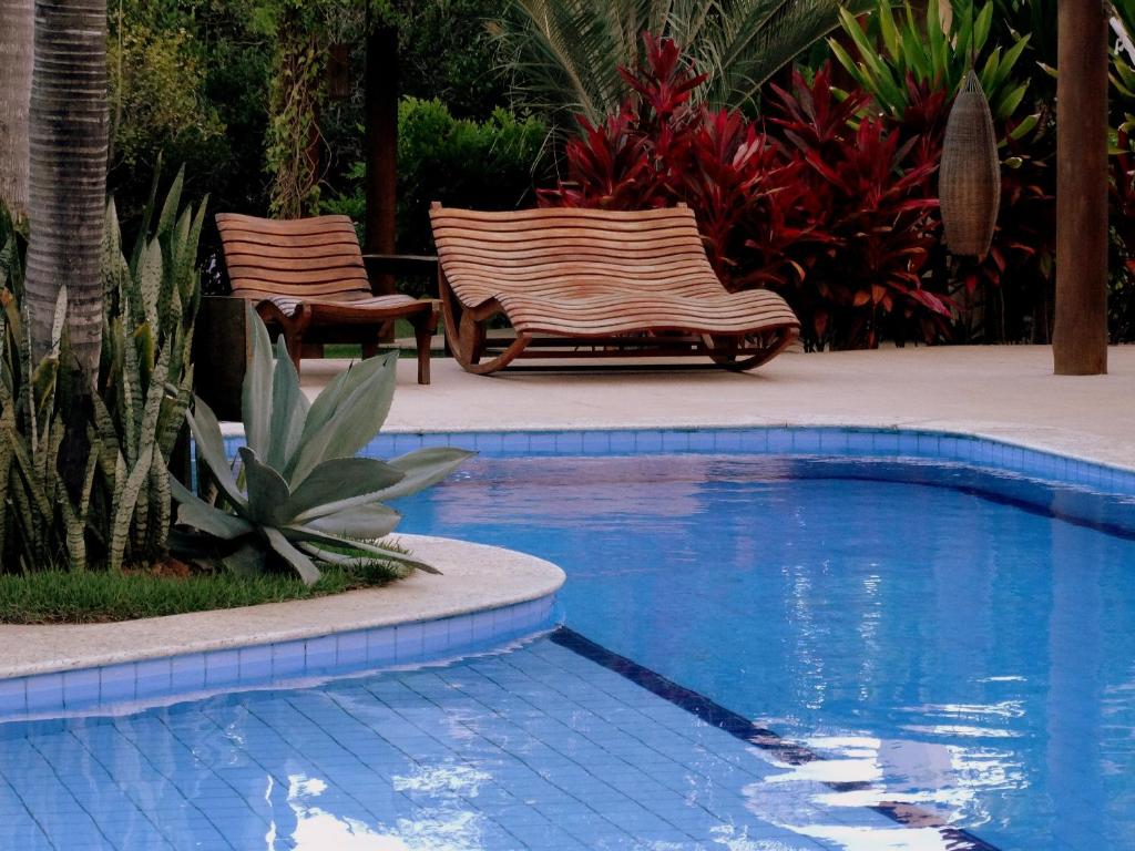 2 sillas sentadas junto a una piscina en Apartamento 2 quartos no Imbassai Breezes, en Imbassai