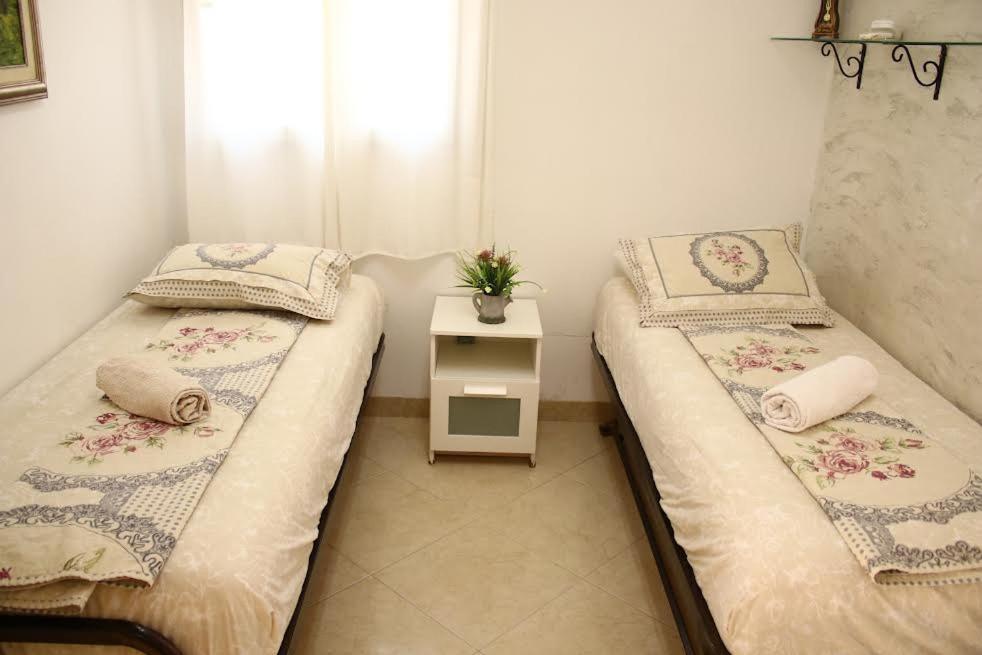 two twin beds in a room with a night stand at בסימטא הצפתית העתיקה in Safed