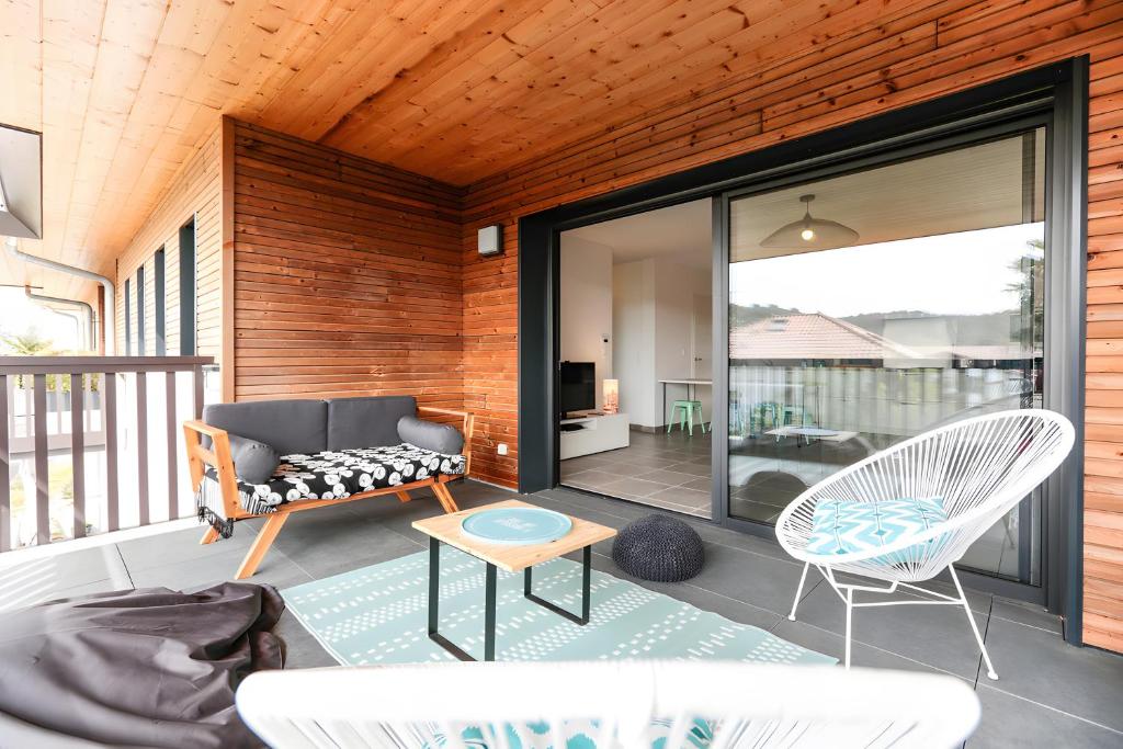 Una sala de estar con un sofá y sillas en un balcón. en Appartement Lumineux avec Terrasse, en Seignosse