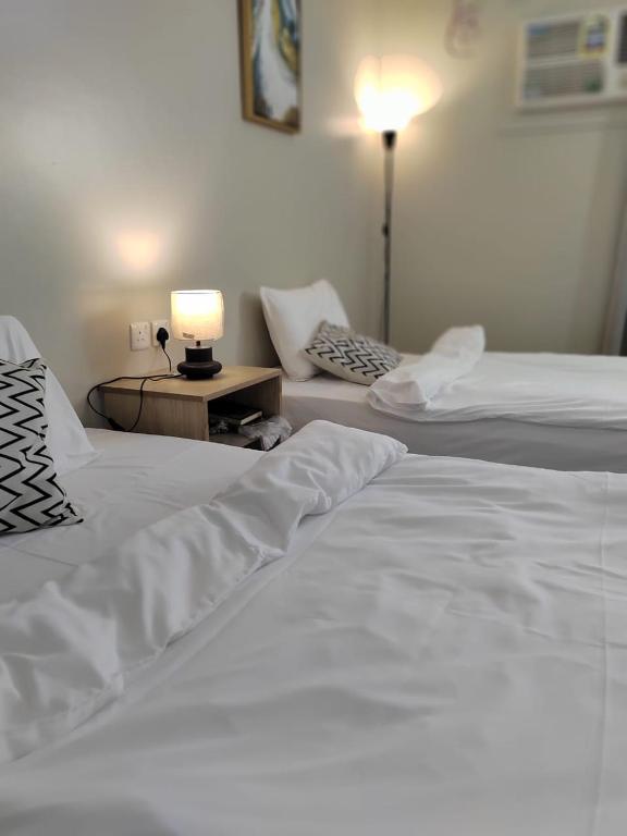 two beds in a hotel room with a lamp on a table at وادي العقيق203 in Al Madinah