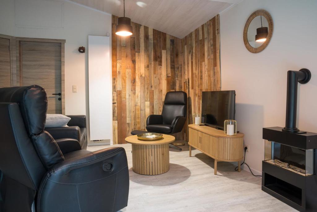 a living room with two chairs and a television at Chalet Bos en Pootjes in Lanaken