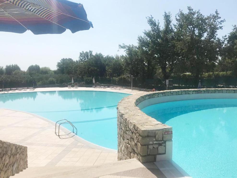 a large swimming pool with a stone wall around it at The Artist - Apartments with Private Garden in Residence with Pool in Manerba del Garda