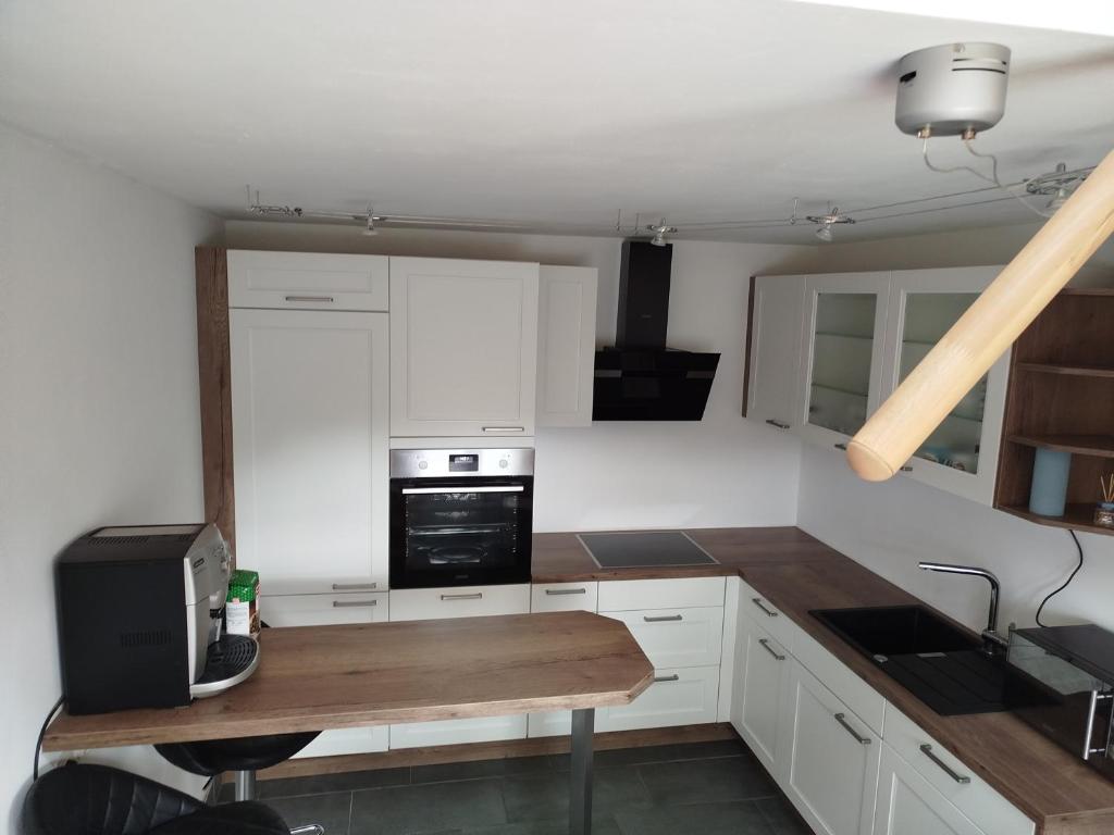 a kitchen with white cabinets and a wooden table at Wohnung im Grünen in Mitterdorf im Mürztal