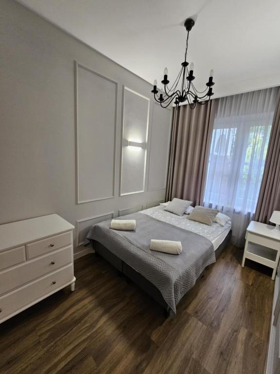 a bedroom with a bed and a dresser and a chandelier at Apartament ,, Studio '' in Nasutów