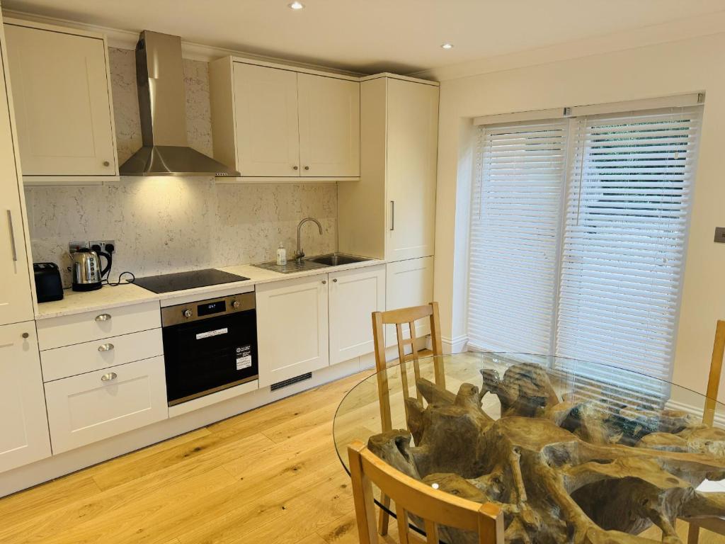 a kitchen with white cabinets and a glass table at Ascot Stylish 3 Bedroom House with Driveway in Ascot