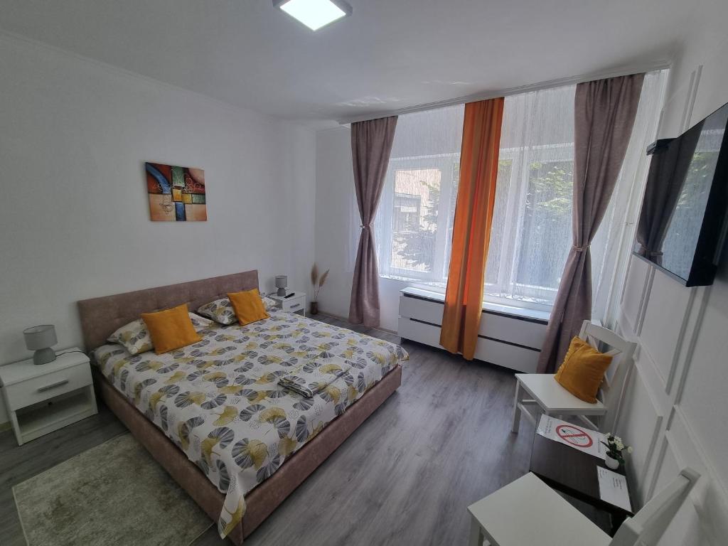 a small bedroom with a bed and two windows at LUX Apartman in Kruševac