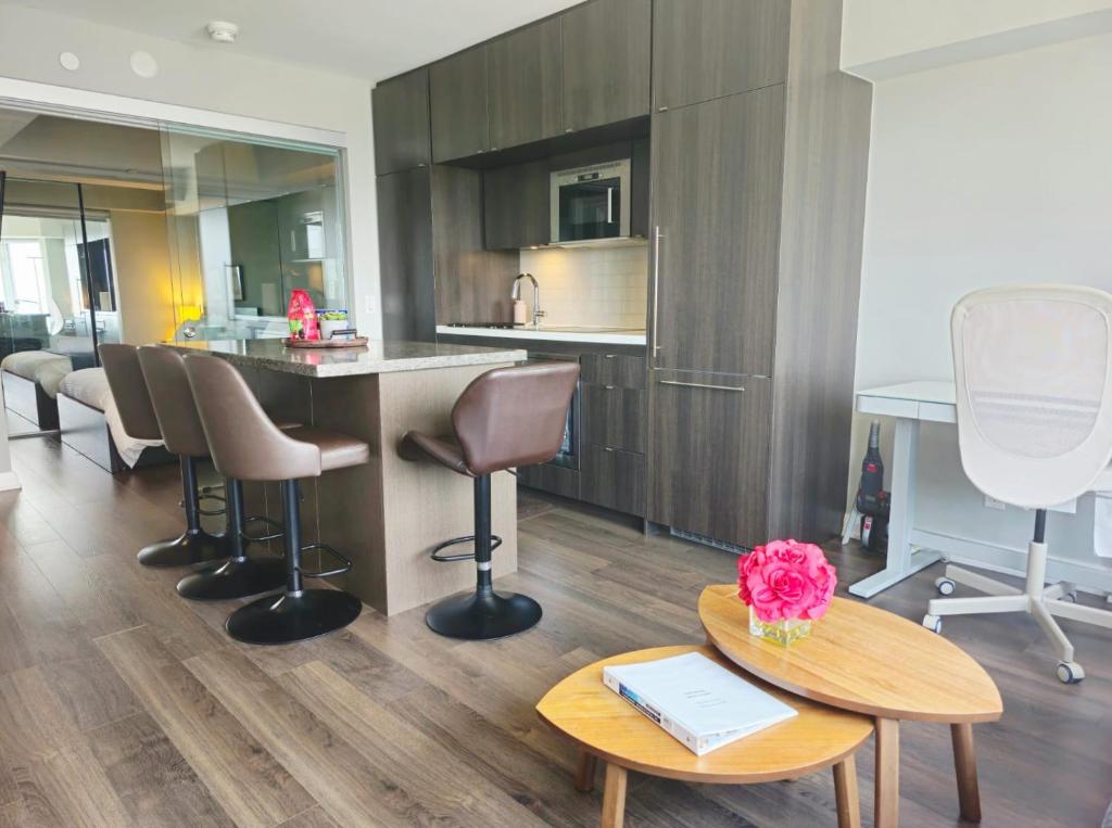 a kitchen with a counter and chairs and a table at Elegant 2BR & 2BA Retreat in Prime Yorkville, Downtown in Toronto