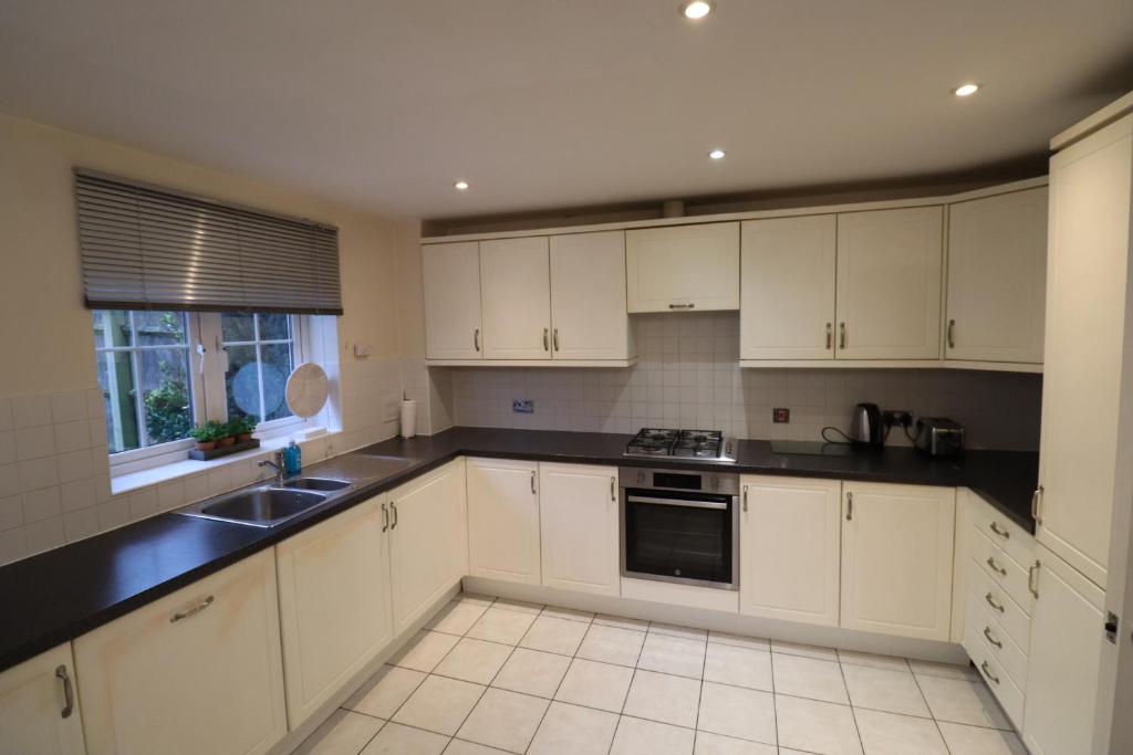 a kitchen with white cabinets and black counter tops at Spacious Bracknell Four Bedroom House in Bracknell