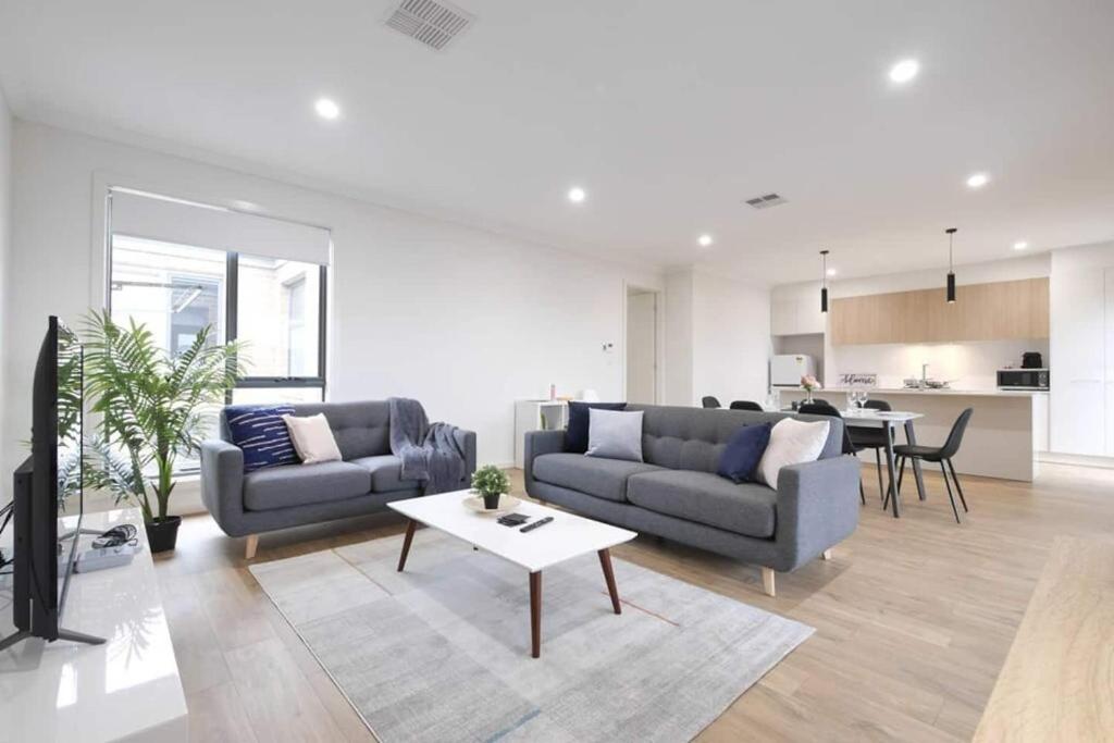 a living room with two couches and a table at No Stairs Dbl Garage Aircon Woodville North in Woodville South