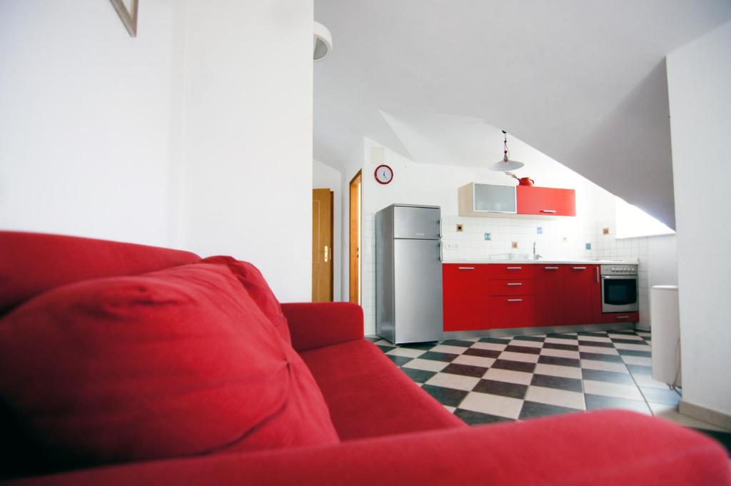 ein Wohnzimmer mit einem roten Sofa und einer Küche in der Unterkunft Apartments Ida Cres in Cres