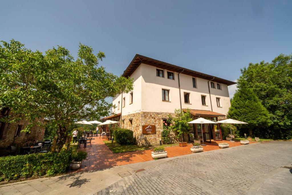 a building with tables and umbrellas in front of it at Urkiola Hotela in Urquiola