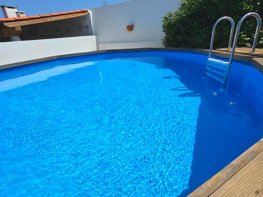 a blue swimming pool with a chair in it at A Casa dos Azulejos in Santiago do Cacém