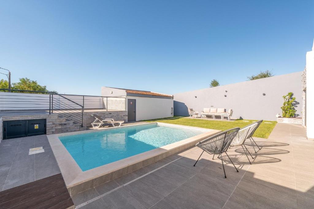 a swimming pool with two chairs and a patio at GuestReady - Villa Belas in Sintra