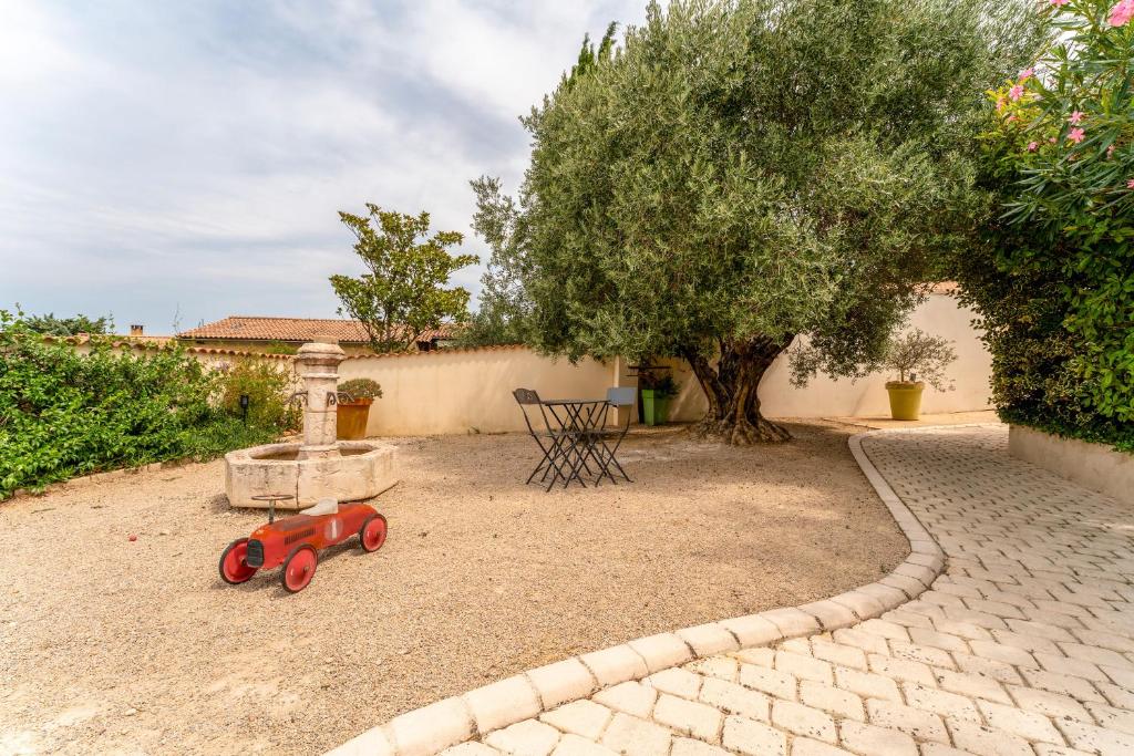 Un tren de juguete rojo sentado en el suelo junto a un árbol. en Gite En Provence, en Saze
