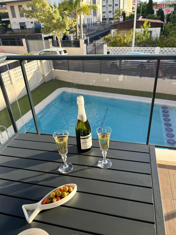 - une bouteille de vin et des verres sur une table à côté de la piscine dans l'établissement Gandia Playa Moderna - nuevo con piscina y parking, 2 banos, playa 300 m, grau 300 m, à Playa de Gandia