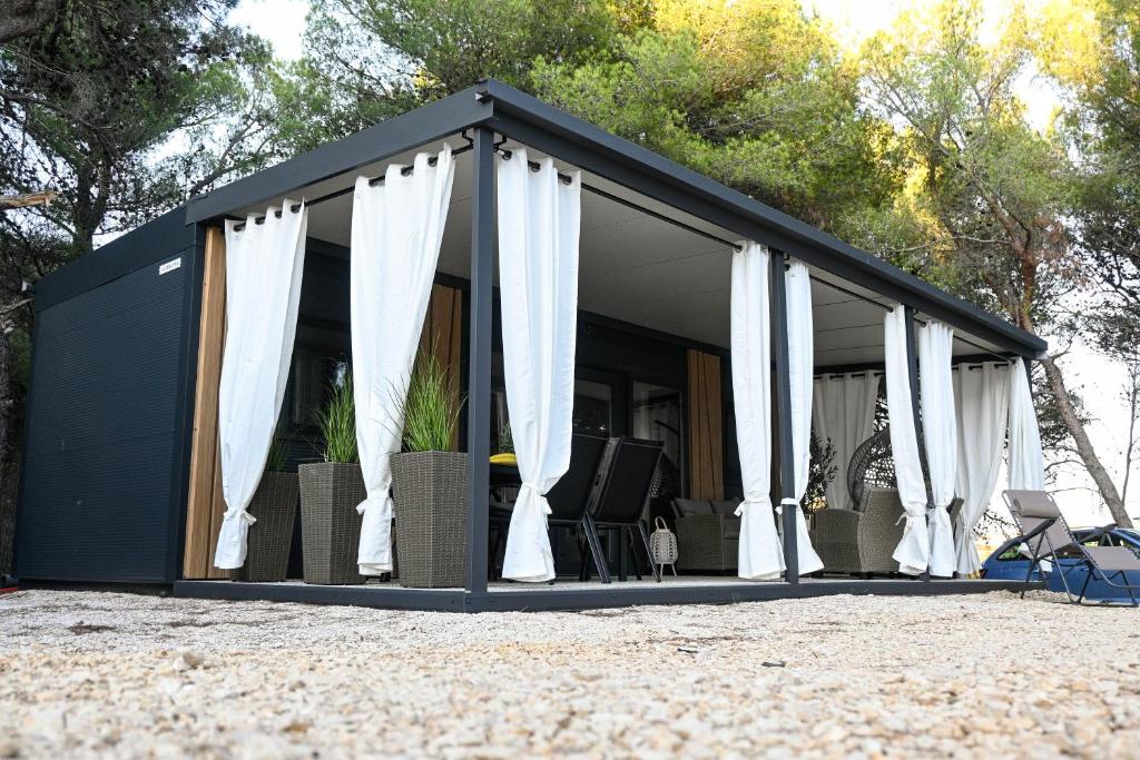 a black container house with white curtains and chairs at Mobile home Periska, Pakoštane in Pakoštane
