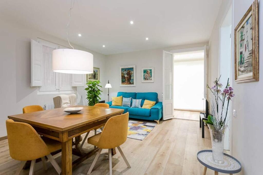 a living room with a wooden table and a blue couch at Lovely Designed House Connected To Center in Cornellà de Llobregat