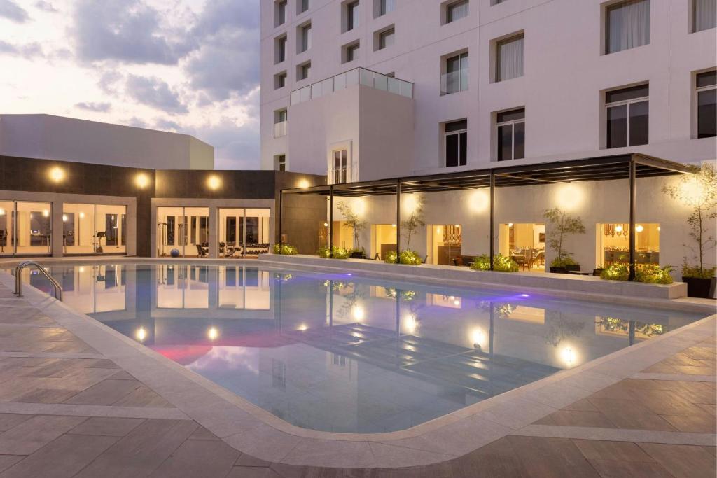 Courtyard by Marriott Puebla Las Animas في بوبلا: مسبح الفندق امام مبنى
