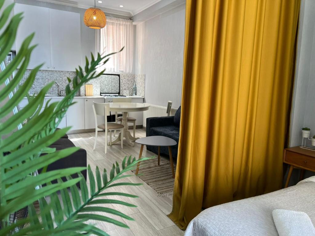 Sala de estar con cortina amarilla y mesa en STUDIO near the Round garden, en Tiflis