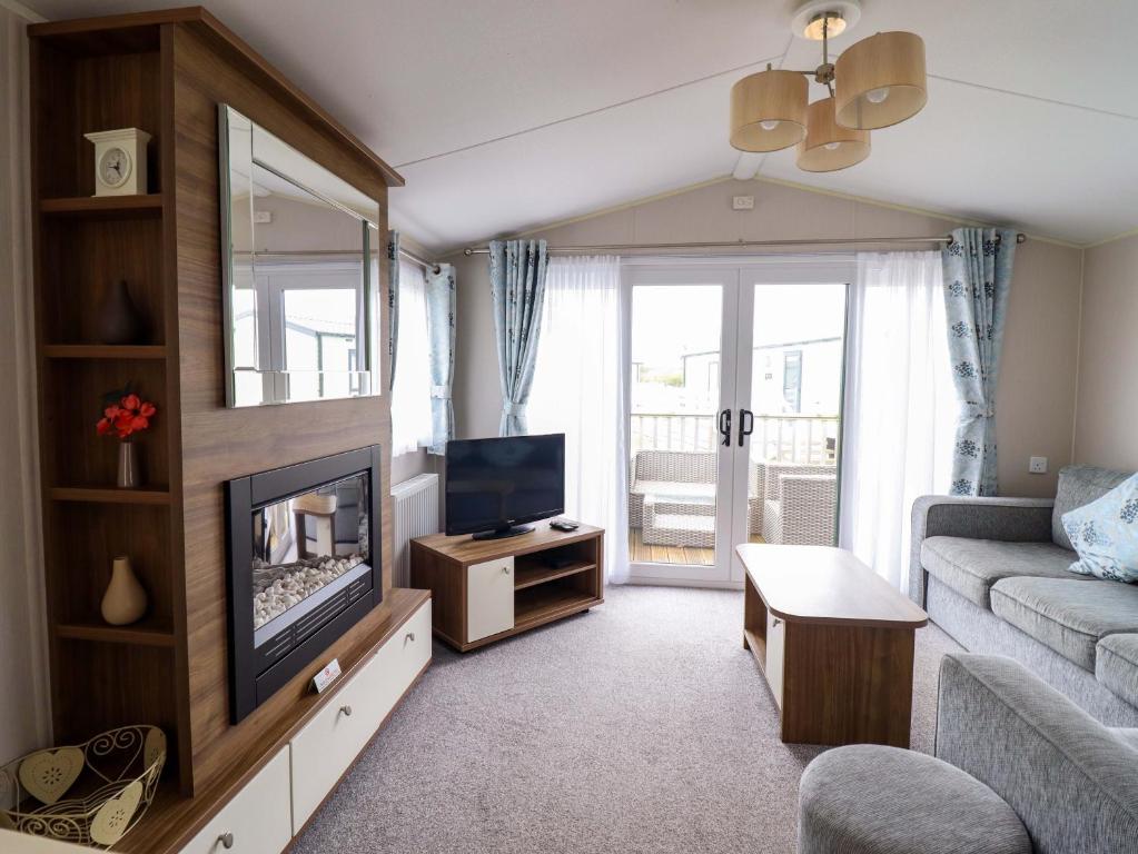a living room with a couch and a television at Sea Breeze C38 Dyffryn Seaside Estate in Dyffryn