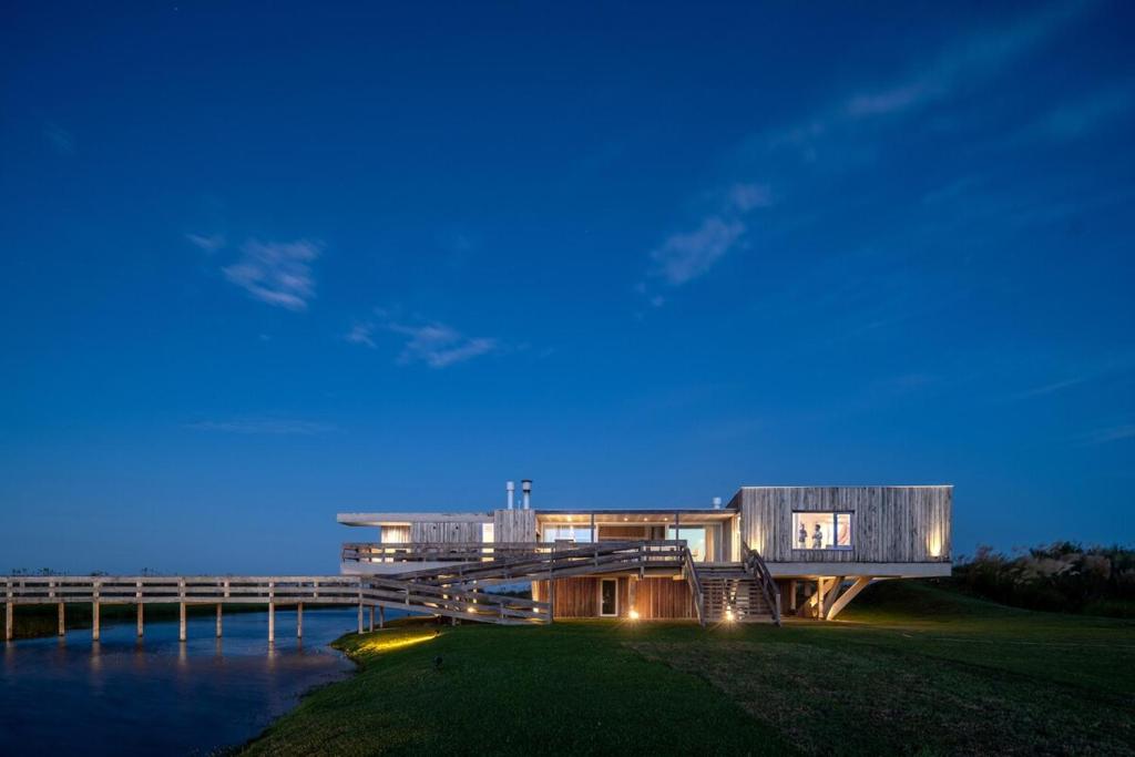 a house on the shore of a body of water at Casa de Lujo Frente al Mar - Chacra Lobos de Mar in Nueva Atlantis