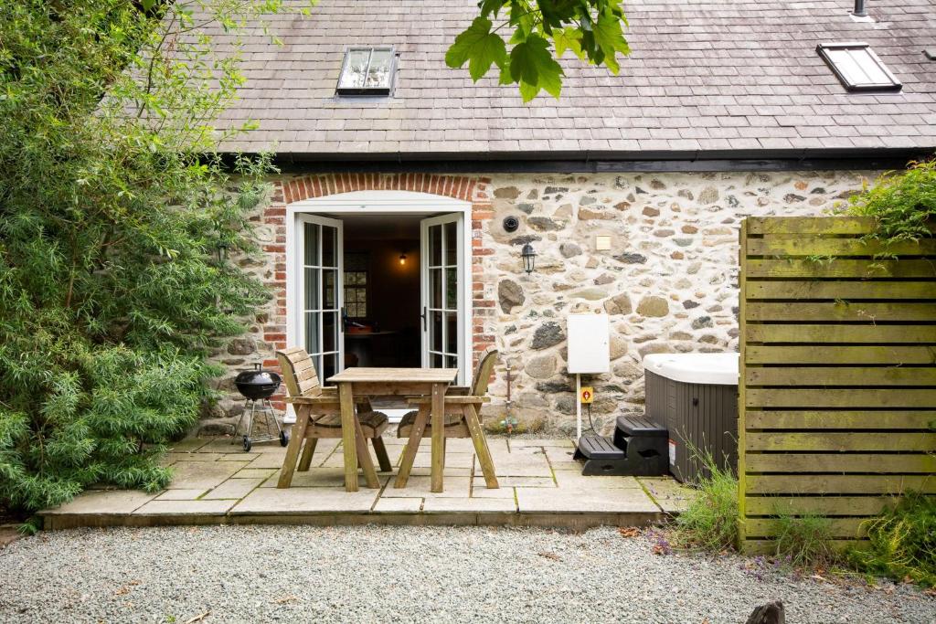 a patio with a table and chairs in front of a building at Rustic Couples Retreat I Hot Tub I Private Estate in Holyhead