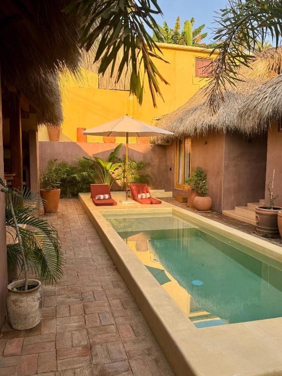 a swimming pool with an umbrella next to a house at Casa Moka in Puerto Escondido