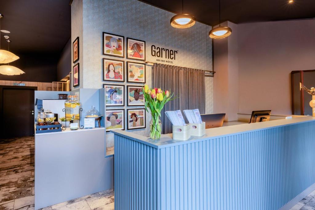 a lobby with a blue counter with flowers on it at Garner Hotel Vienna by IHG in Vienna