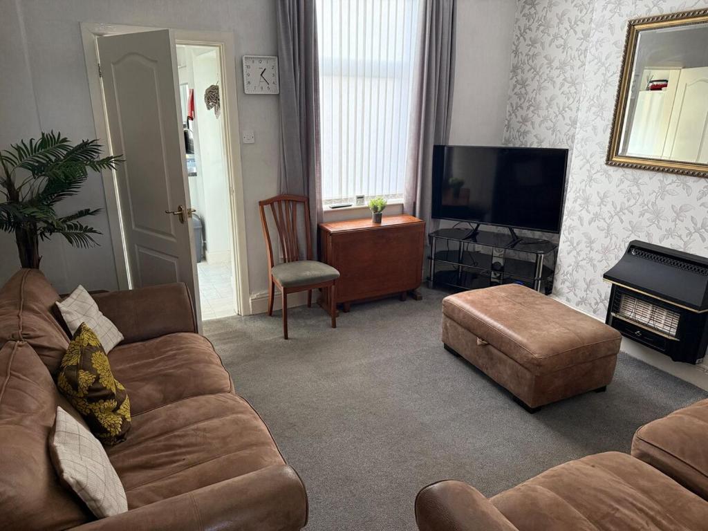 a living room with a couch and a flat screen tv at Large Burnley Townhouse in Burnley