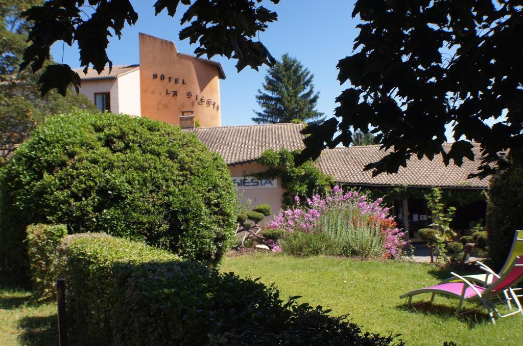 un patio con un edificio y una silla rosa en The Originals City, Hôtel La Siesta, Annonay Est (Inter-Hotel), en Davézieux