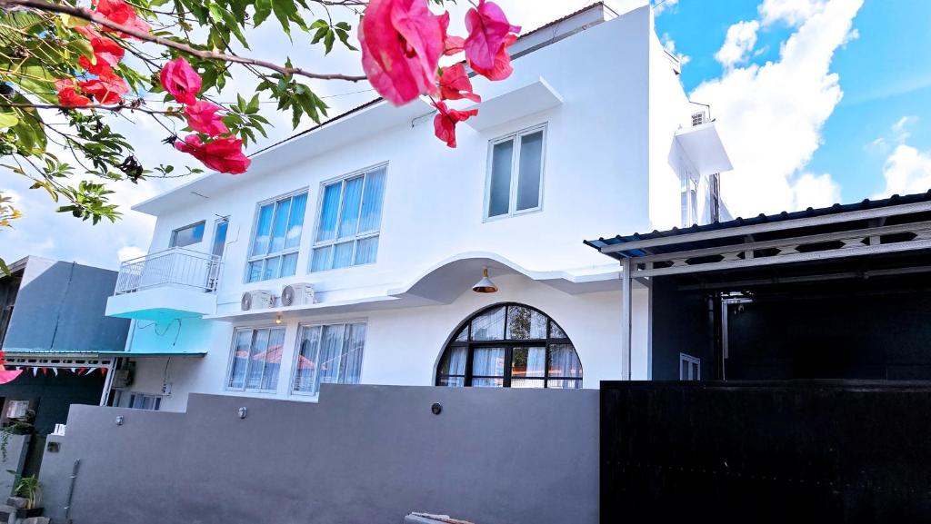 ein weißes Haus mit rosa Blumen davor in der Unterkunft MauLagi Bali Getaway in Jimbaran