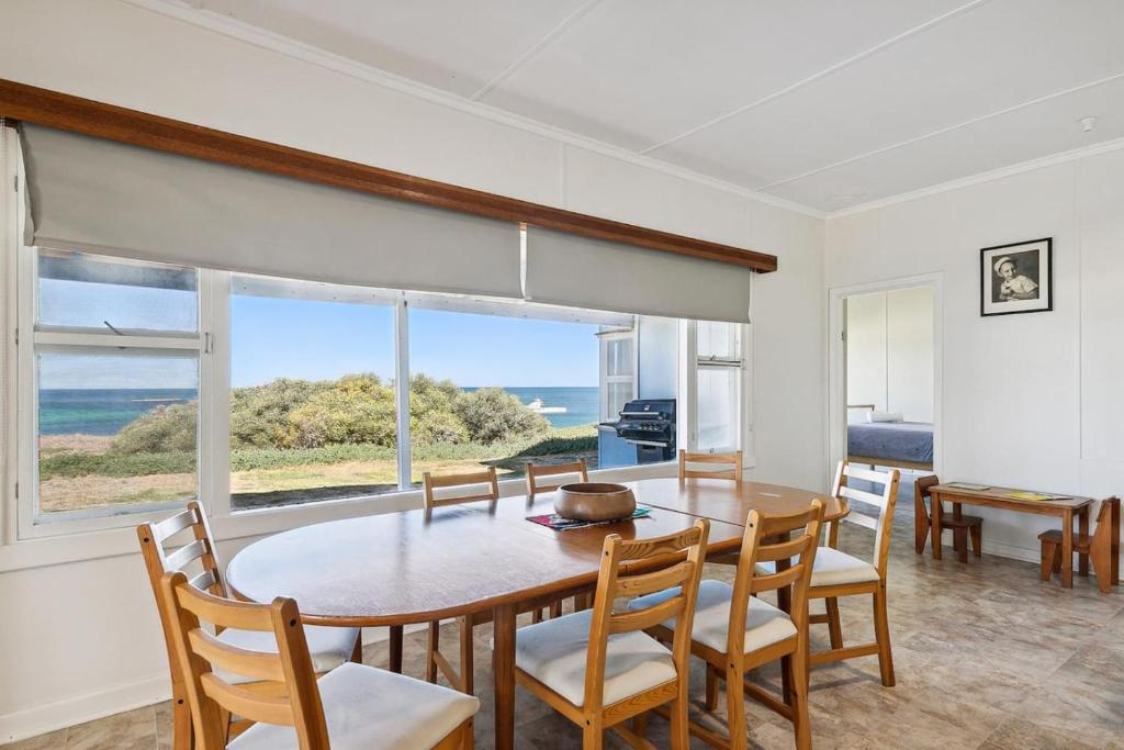 ein Esszimmer mit Tisch und Stühlen und einem Fenster in der Unterkunft The Blue Beach House, 3 star accommodation 5 star view in Ledge Point