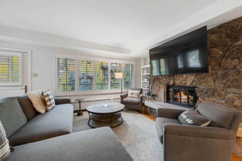 a living room with couches and a stone fireplace at Lodge Tower 487 Three Bedroom Residence in Vail