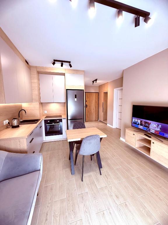 a large kitchen with a wooden table and a television at LOFT APARTAMENT II Kępno in Kępno