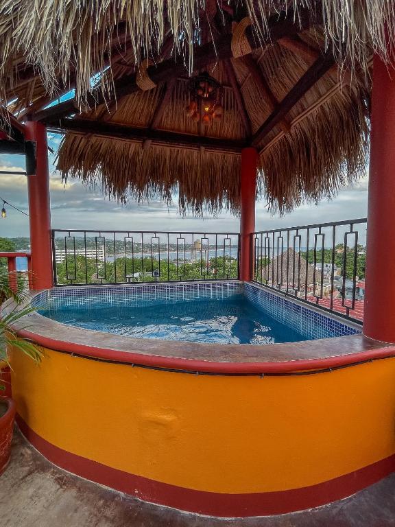 a swimming pool with a thatched roof at Bacanda Hotel in Puerto Escondido