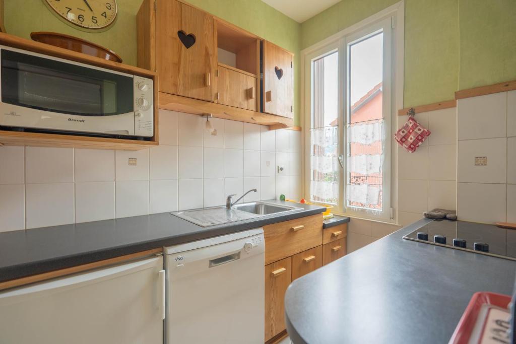 a kitchen with a sink and a microwave at Au Petit Bonheur Proche Centre et Lac in Aix-les-Bains