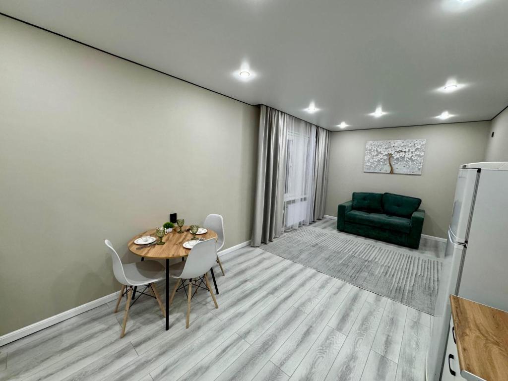 a dining room with a table and a green couch at Апартамент возле Центральной мечети MoD Standart 2-2 in Astana