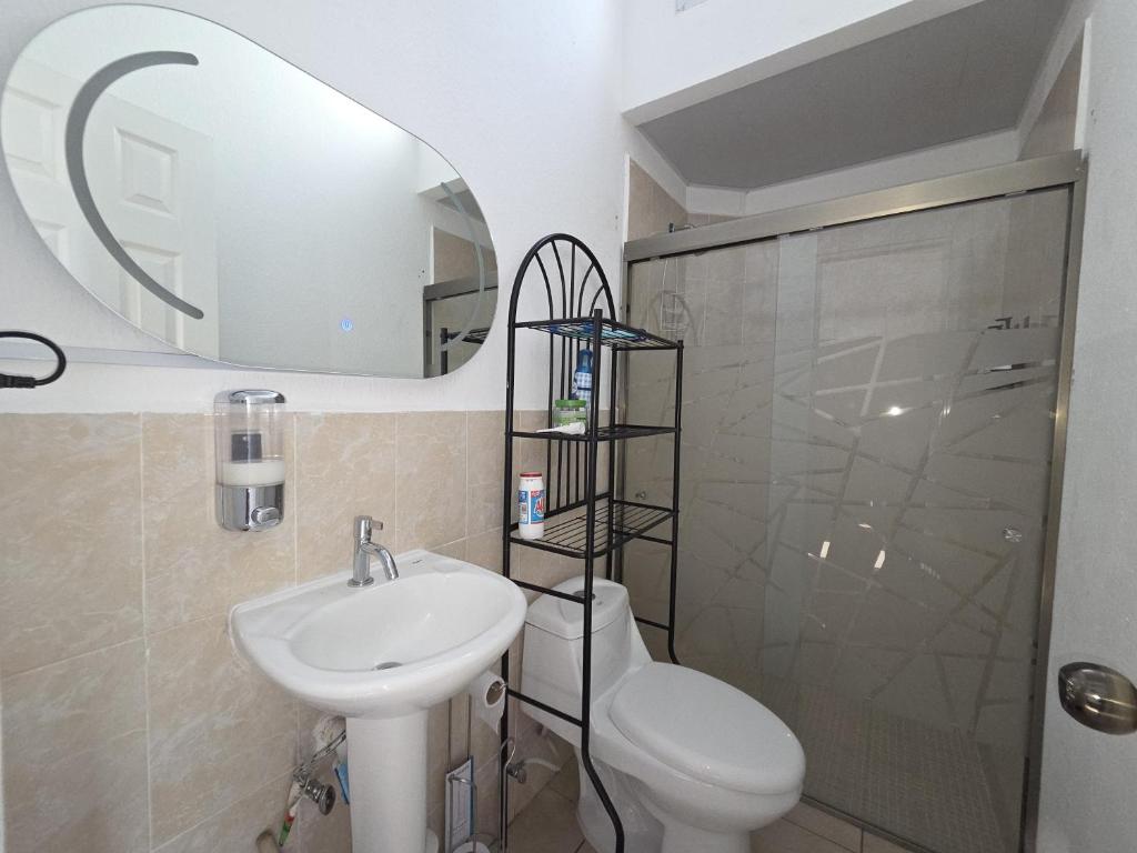 een badkamer met een wastafel, een toilet en een spiegel bij The terrazzo house in Santa Ana