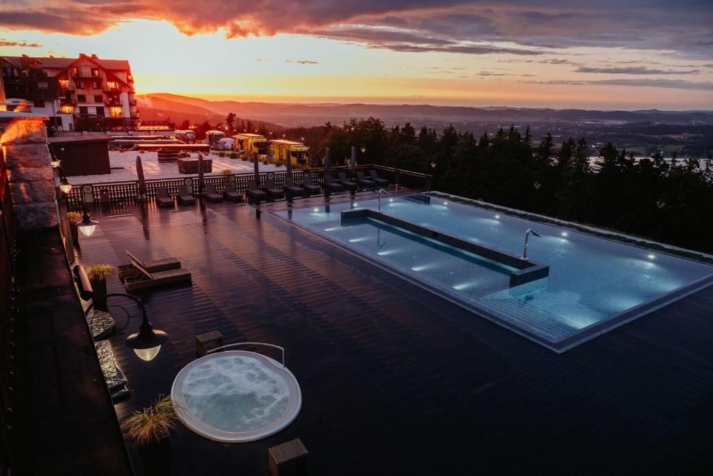 a swimming pool on top of a building with a sunset at Hotel Seidorf in Karpacz