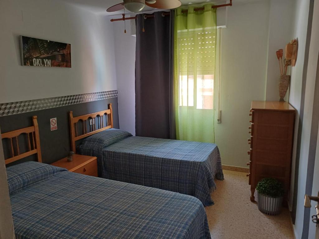 a bedroom with two beds and a window at Apartamentos Mediterráneo en Playa Heliópolis Benicasim in Benicàssim